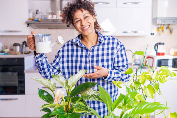 Black woman successful green thumb taking care of home plants - Foto, afbeelding