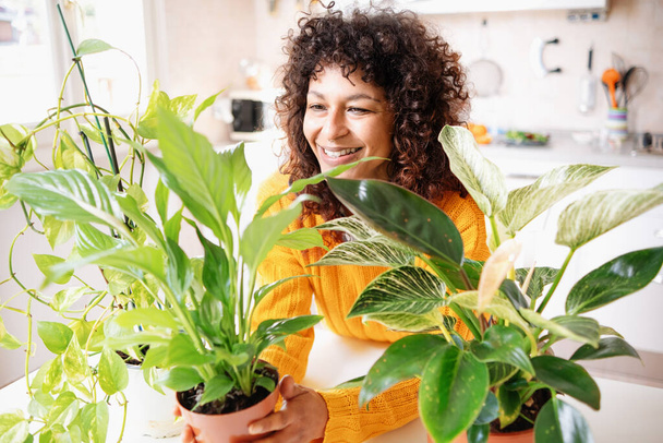 Happy black woman taking care and plant parenting of home plants - Photo, Image