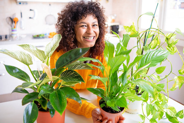 Black woman successful green thumb taking care of home plants - Foto, afbeelding
