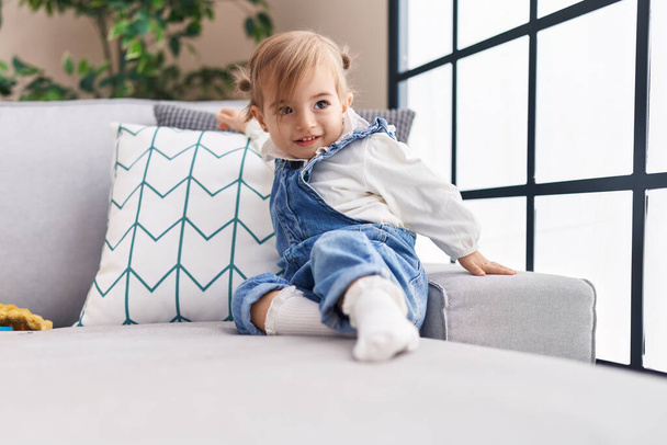 Adorable blonde toddler smiling confident sitting on sofa at home - Photo, Image