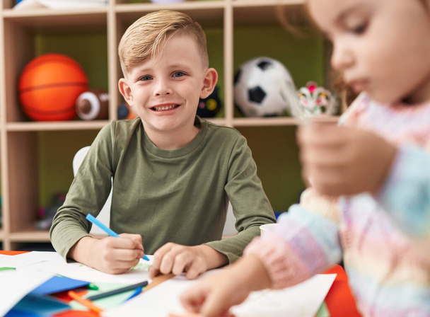 Dos niños preescolares sentados en la mesa dibujando en papel en el jardín de infantes - Foto, imagen
