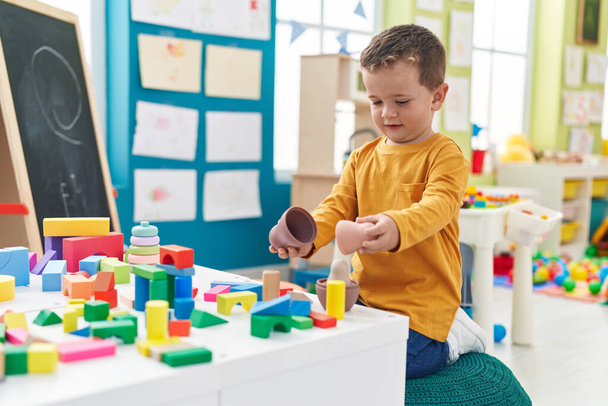 Adorable caucasian boy playing with toys sitting on floor at kindergarten - Zdjęcie, obraz