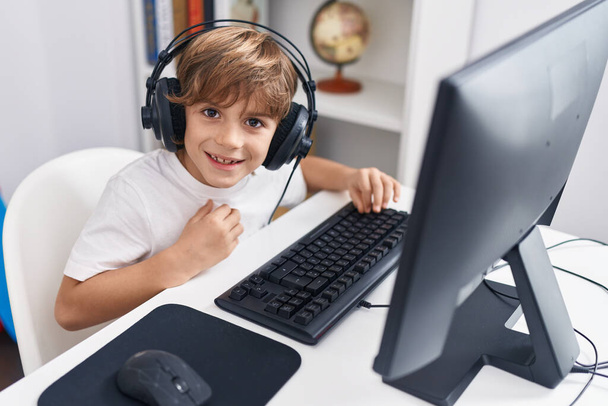 Suloinen valkoihoinen poika opiskelija käyttää tietokonetta istuu pöydällä luokkahuoneessa - Valokuva, kuva