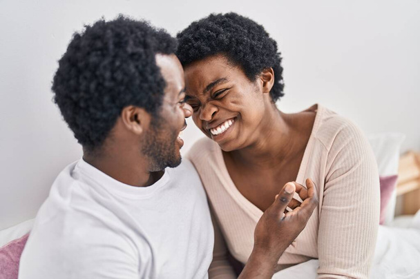Africano americano homem e mulher casal abraçando uns aos outros sentado na cama no quarto - Foto, Imagem