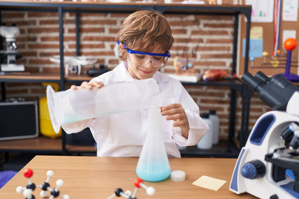 Adorable caucasian boy student pouring liquid on test tube at classroom - Fotografie, Obrázek