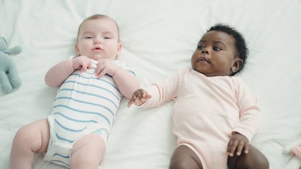 Two adorable babies lying on bed at bedroom - Photo, image