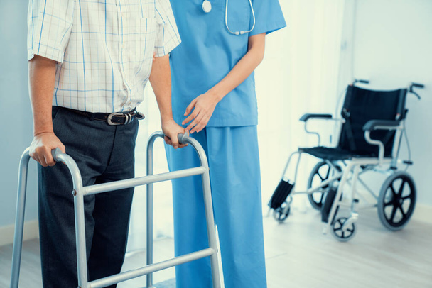 Physiotherapist assists her contented senior patient on folding walker. Recuperation for elderly, seniors care, nursing home. - Fotoğraf, Görsel