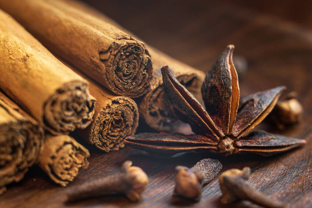 Organic Raw Brown cinnamon sticks Anise star spice fruits and seeds on old wooden table wood stump trunk outdoor walnut plate spoon closeup macro Food Background Vintage Selective Focus - Photo, image