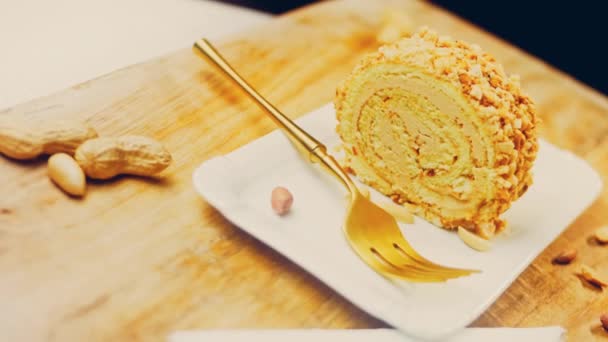 La femme prend un morceau de gâteau roulé avec des cacahuètes avec une fourchette en or. En arrière-plan se trouvent des cacahuètes pelées sur un plateau de cuisson de style rétro. Macro et curseur de tir. - Séquence, vidéo