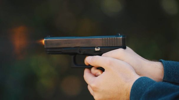 Hands of a man holding a gun Glock and firing. High quality photo - Foto, afbeelding