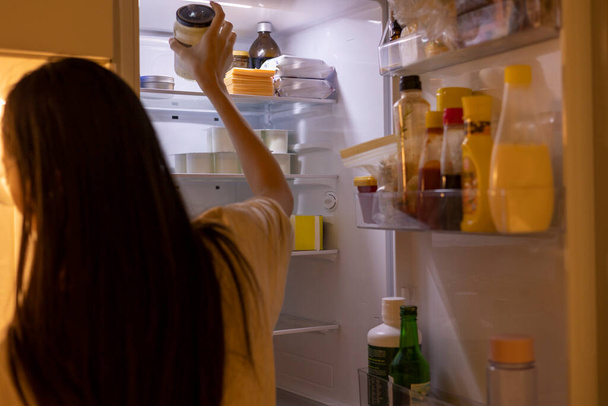 Nainen ottaa pullon keittiön jääkaapista. - Valokuva, kuva