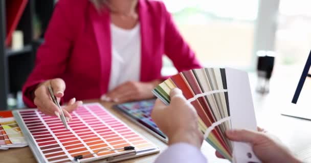 Μια γυναίκα σχεδιάστρια επιλέγει ένα χρώμα παλέτας από έναν πελάτη, ένα κοντινό πλάνο. Σχεδιασμός εσωτερικών χώρων, διαβούλευση - Πλάνα, βίντεο