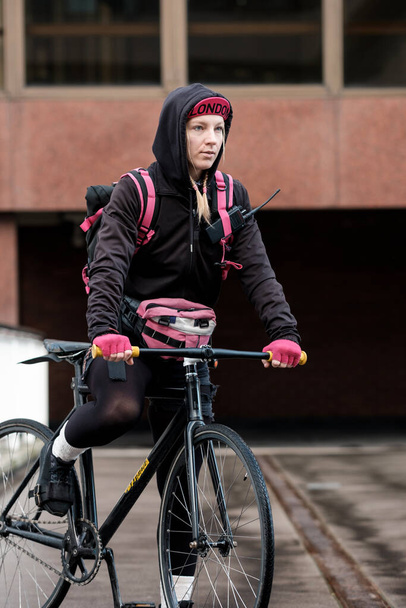 Portrait of bike courier woman still on her bicycle. Ready for work concept. No fumes concept. - Valokuva, kuva