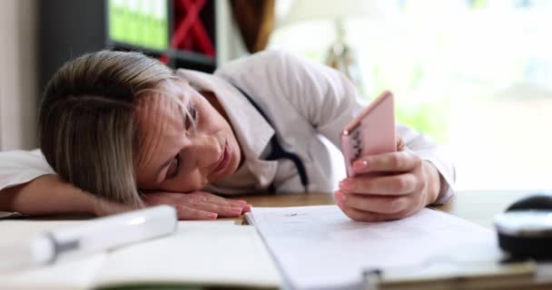 Yorgun bir kadın doktor akıllı telefona bakar, yakın plan, yavaş çekim. Kronik yorgunluk sendromu kavramı - Video, Çekim