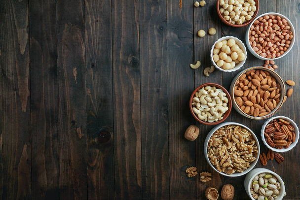 Noten variëteit in de kommen - cashew, hazelnoot, macadamia, pistache, amandel, walnoot, pinda, pecan - Foto, afbeelding