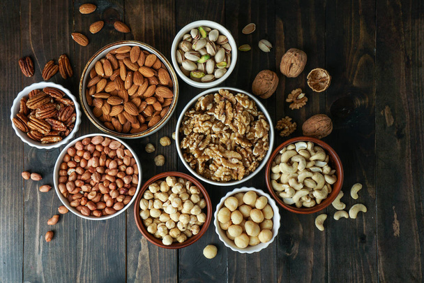 Variedad de frutos secos en los cuencos: anacardo, avellana, macadamia, pistacho, almendra, nuez, cacahuete, pacana - Foto, Imagen