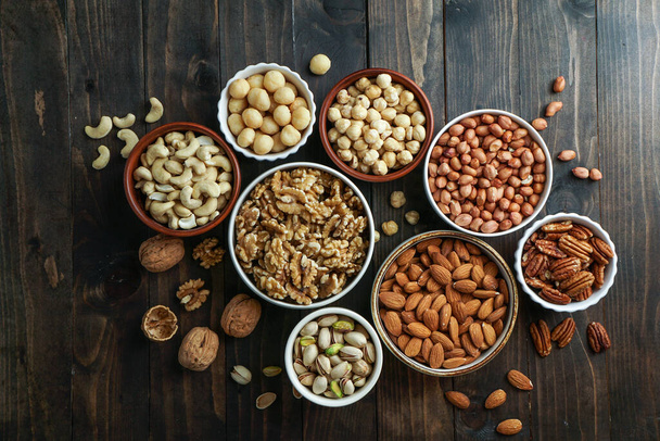 Nuts variety in the bowls - cashew, hazelnut, macadamia, pistachio, almond, walnut, peanut, pecan - Photo, Image