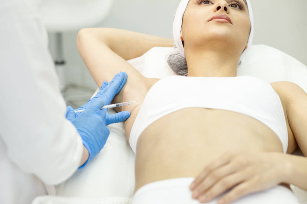 Процедура пупкового ботоксу в клініці косметології, пацієнтка робить ін'єкцію пупкового ботоксу, лікування гіпергідрозу лікарем косметологом, крупним планом
 - Фото, зображення