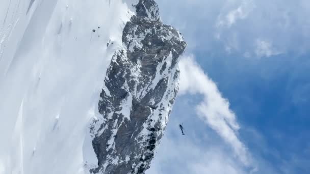LOW ANGLE VIEW: Helicopter flies over snowy peaks and skier starts riding down. Adventurous freeride heliskiing and heliboarding on fresh powder snow in pristine snow-covered Albanian mountain terrain - Filmmaterial, Video