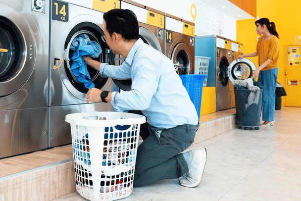 Les Asiatiques qui utilisent une machine à laver à pièces qualifiée dans la salle publique pour laver leurs draps. Concept d'une laveuse et sécheuse commerciale en libre-service dans une salle publique. - Photo, image