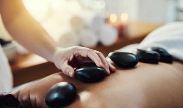 Hot stone massage are a helpful way to ease muscle tension. Closeup shot of a woman getting a hot stone massage at a spa - Valokuva, kuva