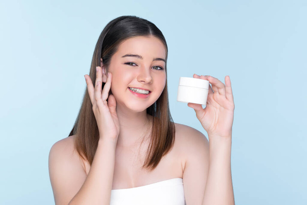 Young charming girl with natural beauty, perfect smooth skin hold lotion, cream, moisturizer jar. Beautiful girl show skincare product smiling on isolated background. - Foto, afbeelding