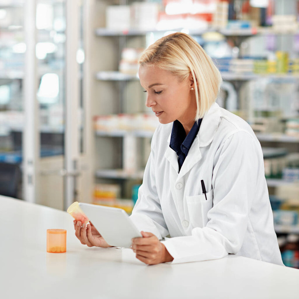 Woman pharmacist in pharmacy, tablet and pill bottle for medical research and check side effects of medicine. Technology, internet with online info on pharmaceutical drugs and health professional. - Foto, imagen