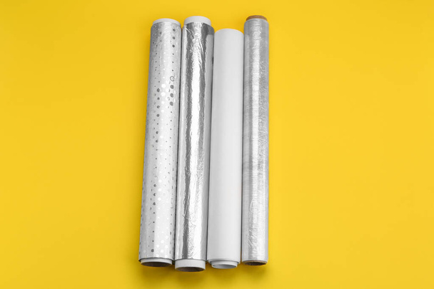 Rolls of aluminium foil, baking paper and food film on yellow background - Foto, immagini