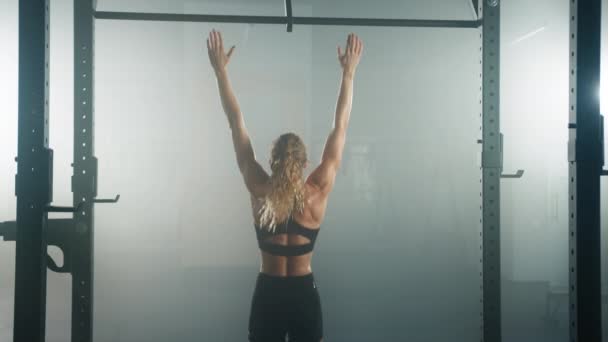 Vahva, omistautunut nainen suorittaa leuka-ups vahvistaa hänen lihaksia. Takaisin näkymä valkoihoinen fitness tyttö aikana hänen aamulla harjoitus istuntoa kuntosalilla. Laadukas 4k kuvamateriaalia - Materiaali, video