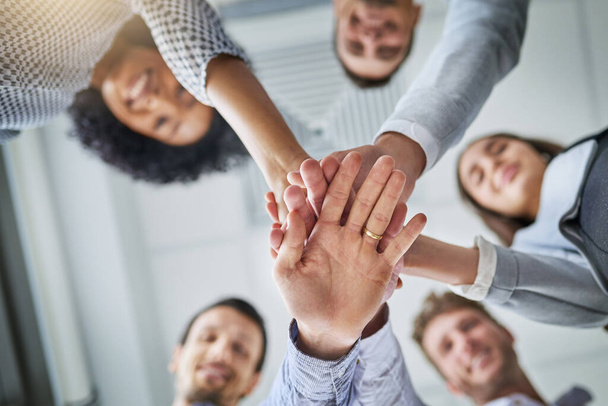 Were here to win. Low angle shot of a group of businesspeople joining their hands in a huddle in an office - Zdjęcie, obraz