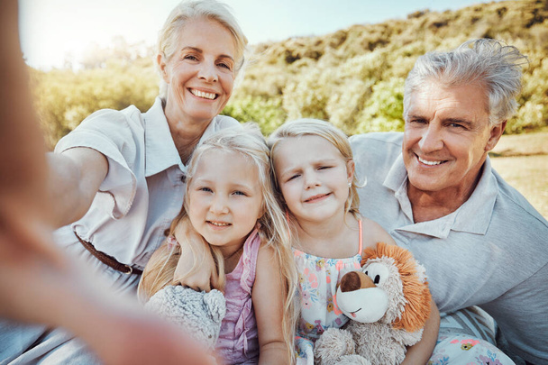 Love, selfie and grandparents with girls in park, smile or loving together for vacation, break or bonding. Portrait, granny or grandfather with granddaughters outdoor, playful or happiness on holiday. - Foto, Bild