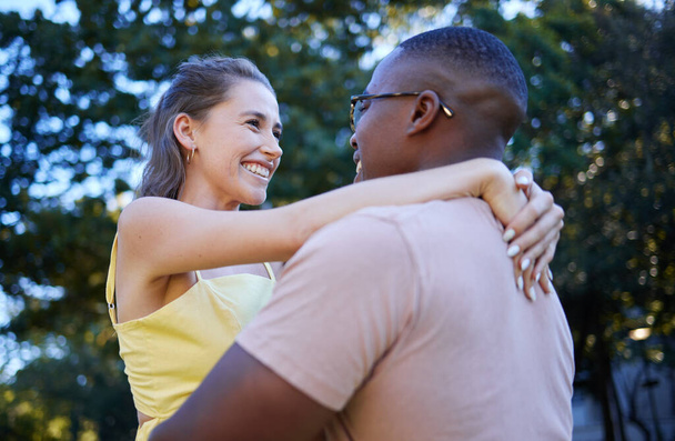 異人種間のカップル、笑顔と愛、ケアや自然公園での関係を受け入れるためのロマンスに抱擁。幸せな黒人男性抱擁女性と笑顔で幸せのためにロマンチックな、抱擁またはサポート外. - 写真・画像