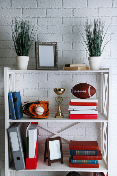 Bookshelves with books and decorative objects on brick wall background - Фото, зображення