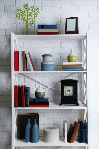Bookshelves with books and decorative objects on brick wall background - Valokuva, kuva