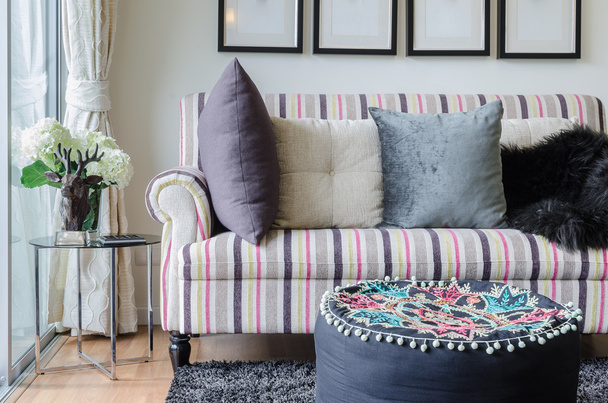 sofá colorido con almohadas y mesa de cristal en la sala de estar
 - Foto, Imagen