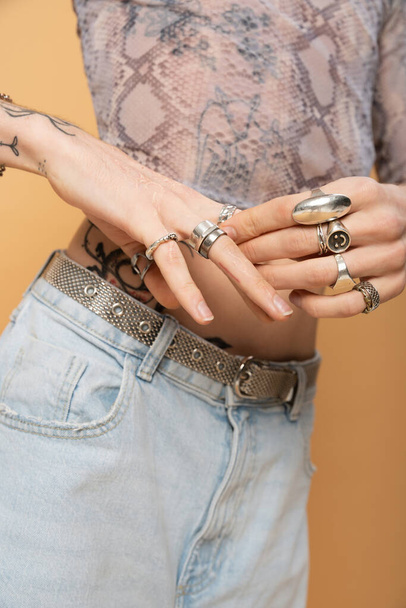 Cropped view of queer person touching rings on fingers isolated on yellow  - Fotografie, Obrázek