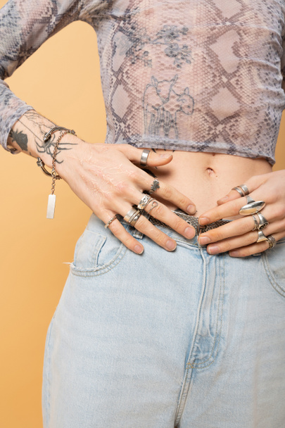 Cropped view of tattooed queer person with accessories isolated on yellow  - Foto, Imagen