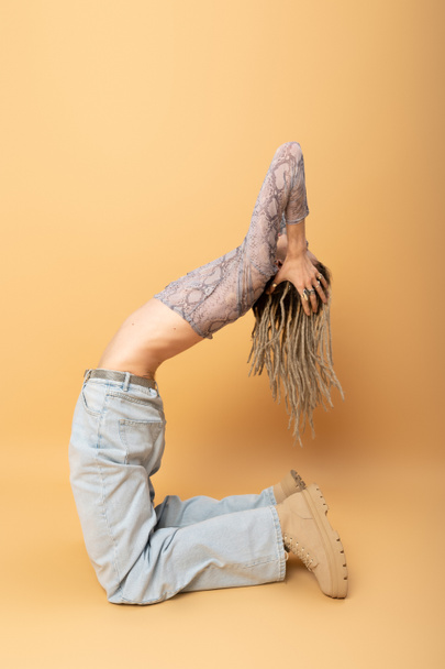 flexible queer person with dreadlocks posing on yellow background  - Foto, immagini