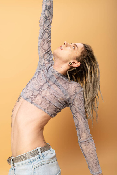 Young queer person in top with animal print posing on yellow background  - Foto, immagini