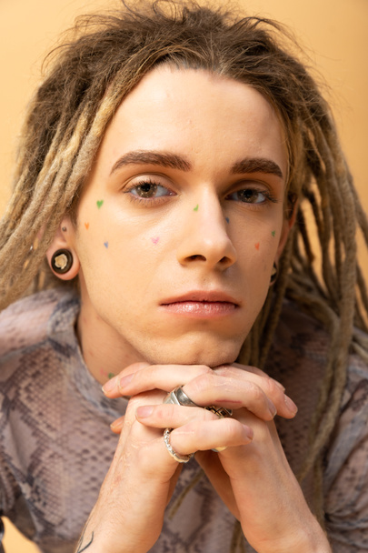 Portrait of young queer person with tattoo on face isolated on yellow  - Fotó, kép