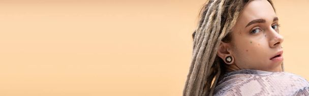 Young nonbinary person with dreadlocks looking at camera isolated on yellow, banner  - Foto, afbeelding