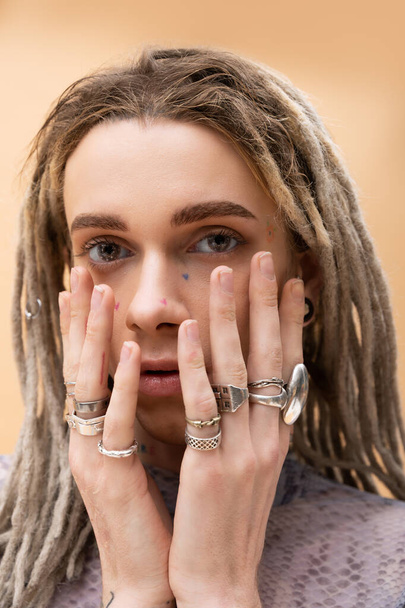 Portrait of queer person with rings on fingers looking at camera isolated on yellow  - Photo, image