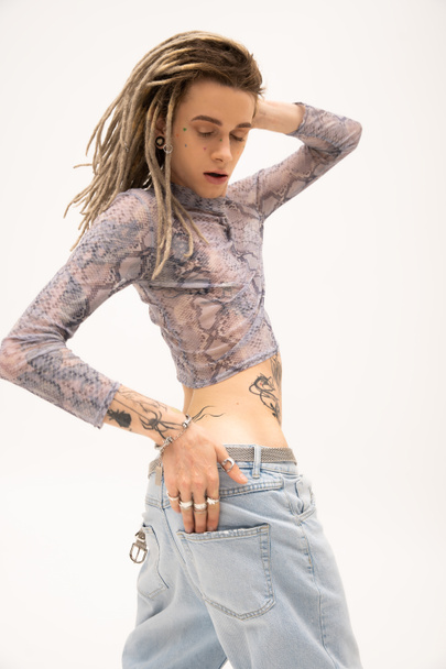 Trendy queer person in jeans and crop top with animal print posing isolated on white  - Zdjęcie, obraz