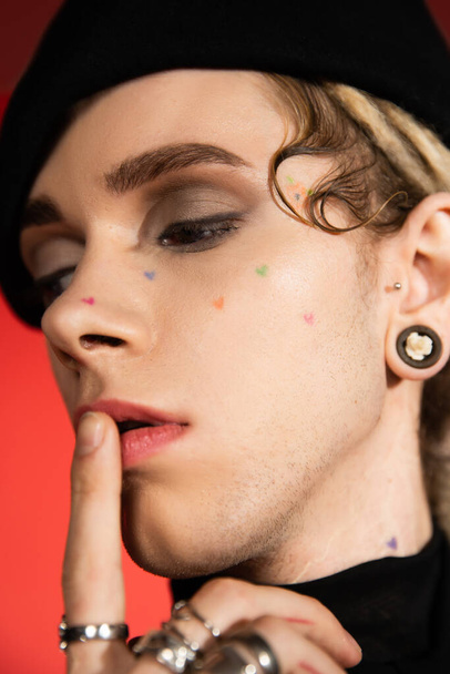 close up portrait of tattooed queer person with makeup touching lips isolated on orange - Foto, Imagem