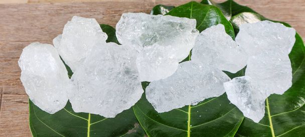 Crystal clear alum cubes or Potassium alum on green leaves chemical compound substance concept for beauty spa and underarm treatment industrial                                - Foto, Imagem
