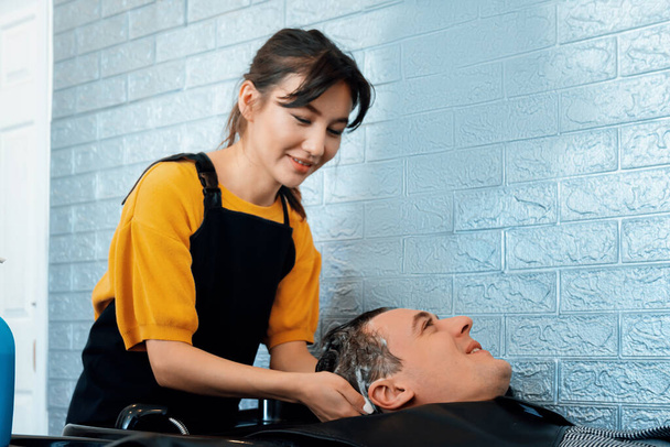 Kaukasische Mann bekommt Haarwäsche von professionellen Friseur mit Shampoo fühlt sich entspannt und bequem. Diplom-Friseurin mit Friseursalon, Friseursalon mit Friseurkonzept. - Foto, Bild