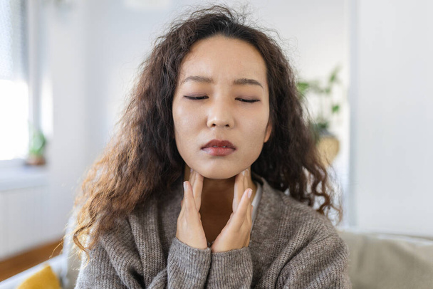 Close up of young Asian woman rubbing her inflamed tonsils, tonsilitis problem, cropped. Woman with thyroid gland problem, touching her neck, girl has a sore throat - Photo, Image