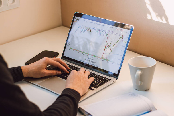 Young casual entrepreneur examines the effects of world events on the charts of the world's leading stock market indices. The life of a stock trader. - Fotoğraf, Görsel