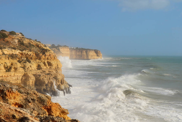 大西洋の大きな波とポルトガル南部で暖かく、風の強い冬の日に崖の上に飛び散る. - 写真・画像