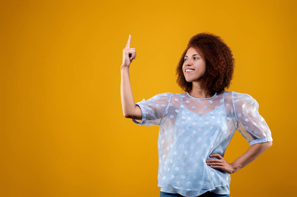 Look up. Cute young woman in a white blouse pointing her finger up - Foto, Imagen